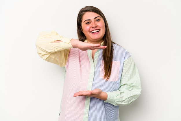 Foto giovane donna caucasica sovrappeso isolata su sfondo bianco che tiene qualcosa con entrambe le mani presentazione del prodotto