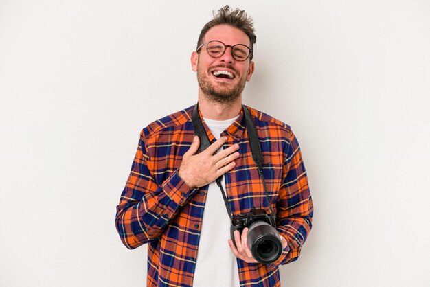 Young caucasian photograph man isolated on white background laughs out loudly keeping hand on chest.