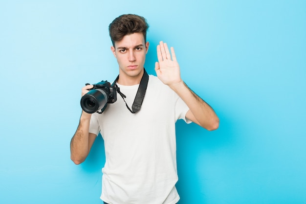 Young caucasian photographer man holding a camera