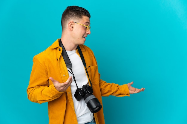 Young  caucasian photographer man isolated on blue wall with surprise expression while looking side