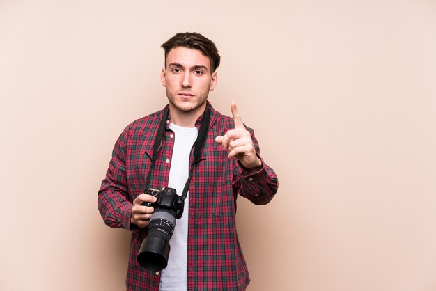 Photo young caucasian photographer man isolated showing number one with finger.