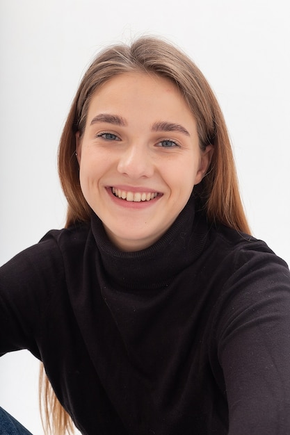 Young caucasian pretty girl with long hair in black turtleneck at white studio