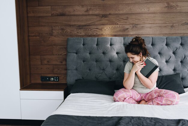 Young caucasian pretty woman with a book on her bed