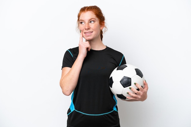 Молодой кавказский рыжеволосый футболист женщина изолирована на белом фоне, думая об идее, глядя вверх