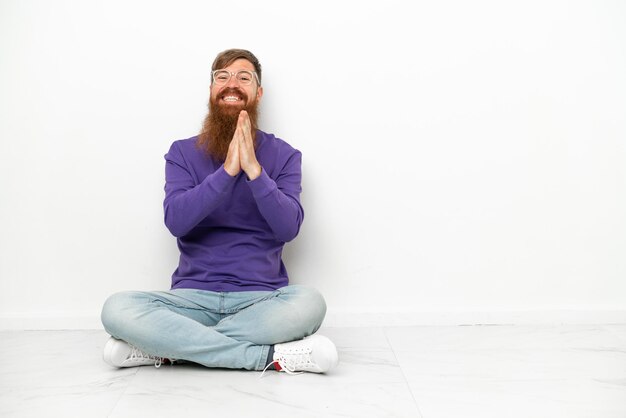 Young caucasian reddish man sitting on the floor isolated on white background applauding after presentation in a conference