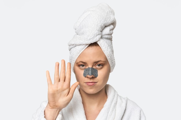 Young Caucasian redhead with pore strip standing with outstretched hand showing stop sign