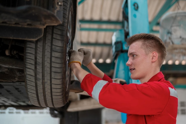 Young caucasian repairman analyzing and fixing broken car in car repair mechanic shop