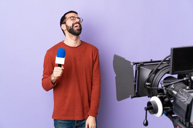 Young caucasian reporter man over isolated purple wall