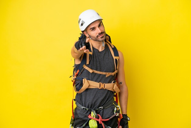 Young caucasian rock climber man isolated on yellow background points finger at you with a confident expression