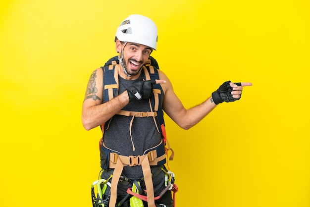 Young caucasian rock climber man isolated on yellow background surprised and pointing side