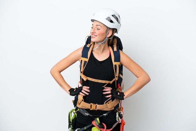 Young caucasian rock climber woman isolated on white background
posing with arms at hip and smiling