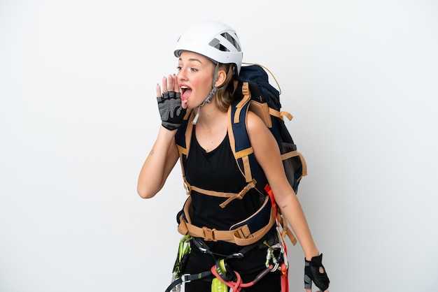 Young caucasian rock climber woman isolated on white background
shouting with mouth wide open to the lateral