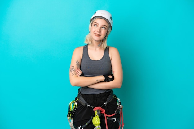 Young caucasian rockclimber woman isolated on white background looking up while smiling