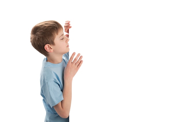 Photo young caucasian schoolboy peeking out from blank copy space boy with an empty poster copy space