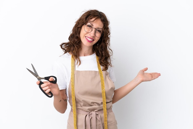 Young caucasian seamstress woman isolated on white background extending hands to the side for inviting to come