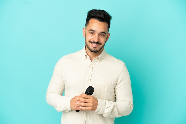 Young caucasian singer man isolated on blue background