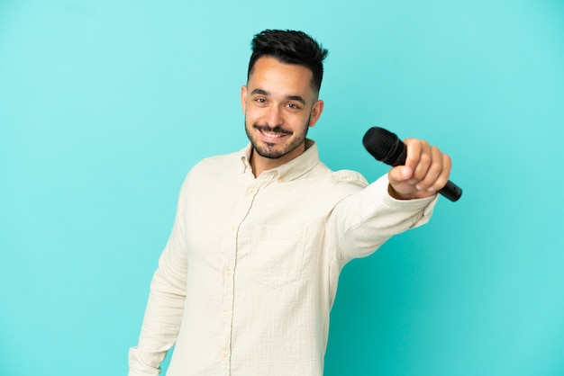 Young caucasian singer man isolated on blue background