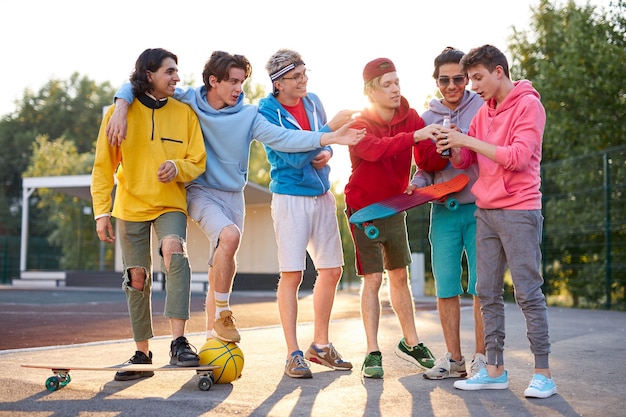 Young caucasian skateboarders drink juice outdoors