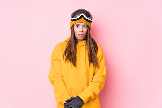 Young caucasian skier woman isolated shrugs shoulders and open eyes confused