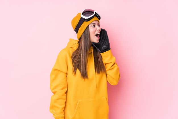 Photo young caucasian skier woman shouting and holding palm near opened mouth.