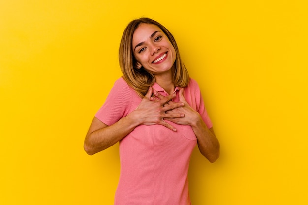 Young caucasian skinny woman  has friendly expression, pressing palm to chest. Love concept.