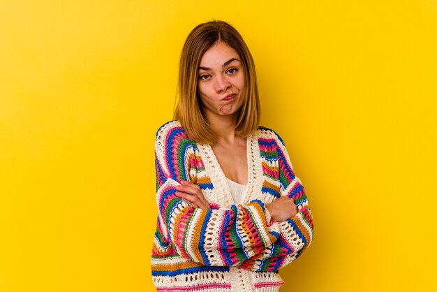 Young caucasian skinny woman isolated on yellow background blows cheeks, has tired expression. Facial expression concept.