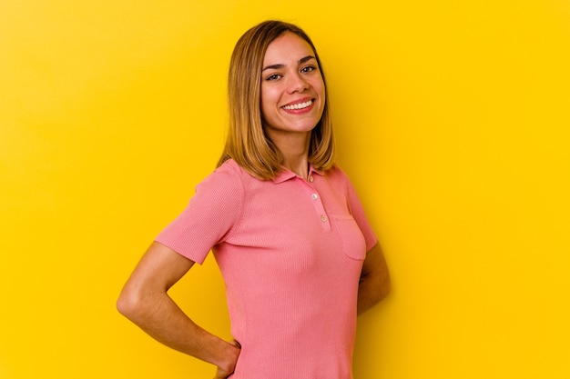 Young caucasian skinny woman isolated on yellow confident keeping hands on hips.