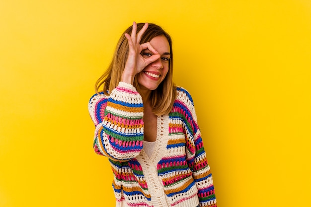 Young caucasian skinny woman isolated on yellow excited keeping ok gesture on eye.