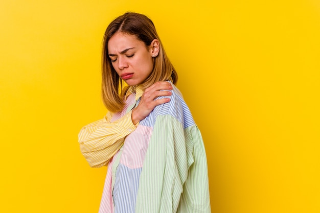 Young caucasian skinny woman isolated on yellow wall having a shoulder pain