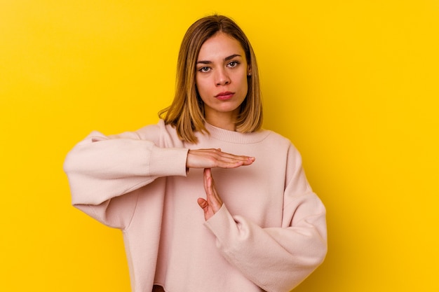 Young caucasian skinny woman isolated on yellow wall showing a timeout gesture