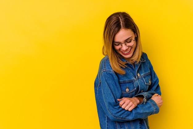 Young caucasian skinny woman isolated on yellow wall smiling confident with crossed arms