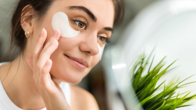 A young caucasian smiling woman with patches under her eyes Skin care theme