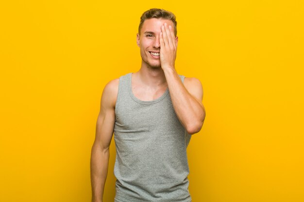 Young caucasian sport man having fun covering half of face with palm.