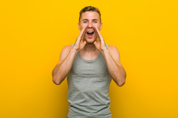 Young caucasian sport man shouting excited to front.