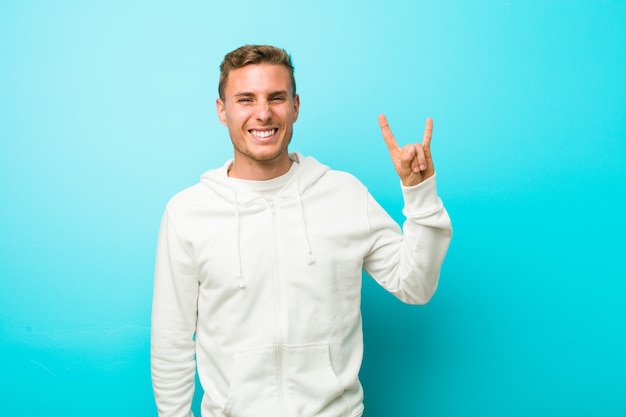 Photo young caucasian sport man showing a horns gesture as a revolution concept.