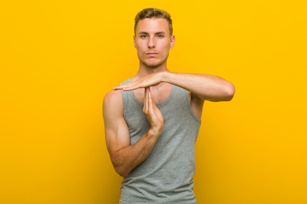 young caucasian sport man showing a timeout gesture.