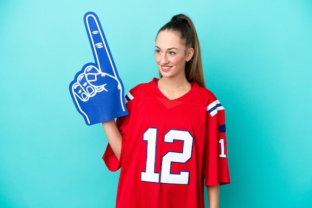 Young caucasian sport woman isolated on blue background looking to the side and smiling