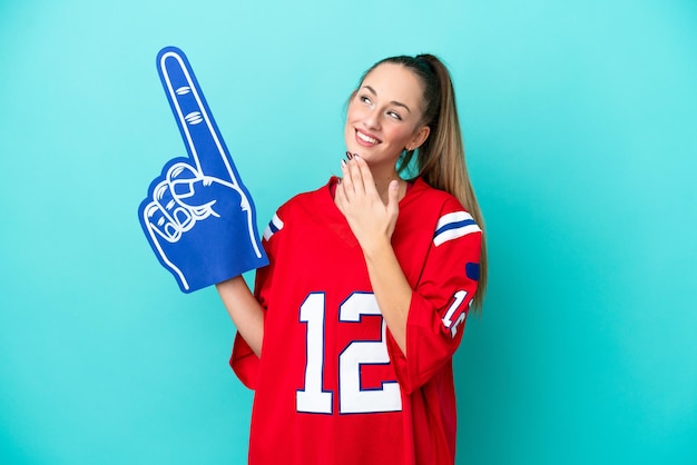 Young caucasian sport woman isolated on blue background looking up while smiling