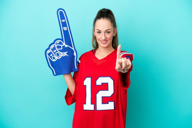 Young caucasian sport woman isolated on blue background showing and lifting a finger