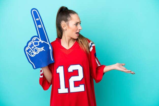 Young caucasian sport woman isolated on blue background with surprise expression while looking side