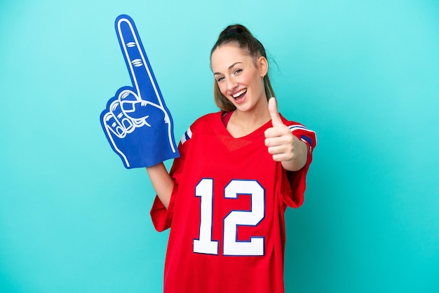 Young caucasian sport woman isolated on blue background with thumbs up because something good has happened