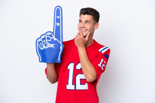 Young caucasian sports fan man isolated on white background looking up while smiling