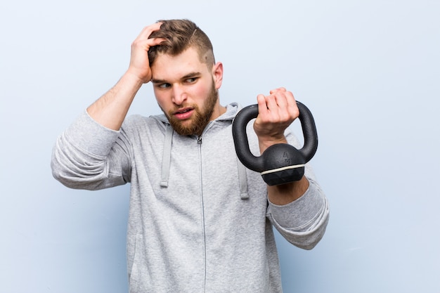 Young caucasian sportsman holding a dumbbell being shocked, she has remembered important meeting.