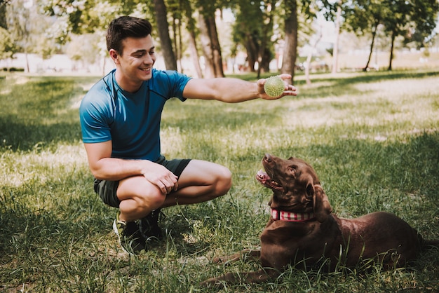 Foto giovane sportivo caucasico con il suo cane nel parco verde.