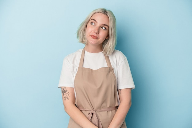 Young caucasian store clerk woman isolated on blue background dreaming of achieving goals and purposes