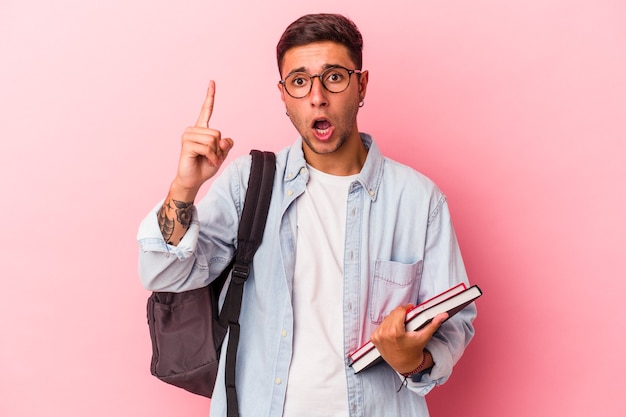 Young caucasian student man holding books isolated on pink background  having an idea, inspiration concept.