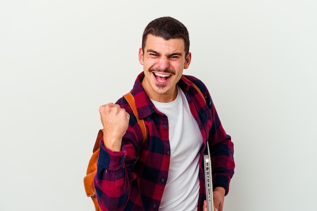 Young caucasian student man holding a laptop isolated on white background cheering carefree and excited. Victory concept.