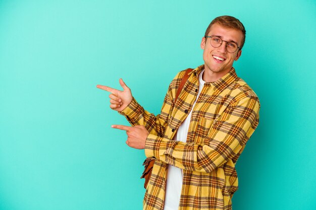 Young caucasian student man isolated on blue background excited pointing with forefingers away.