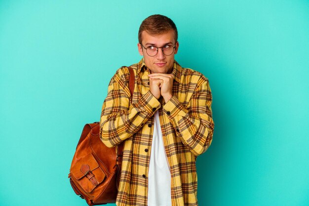 Young caucasian student man isolated on blue background