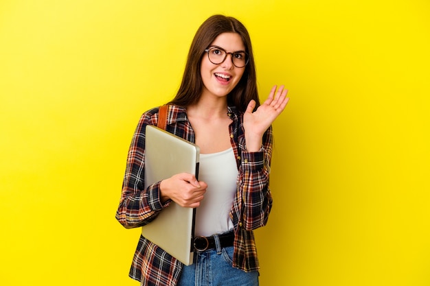 Young caucasian student woman holding a laptop isolated on pink background surprised and shocked.